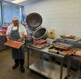 Person mit Schürze hält ein Backblech in Händen
