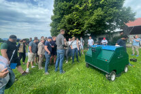 Personen stehen auf Wiese neben Roboter